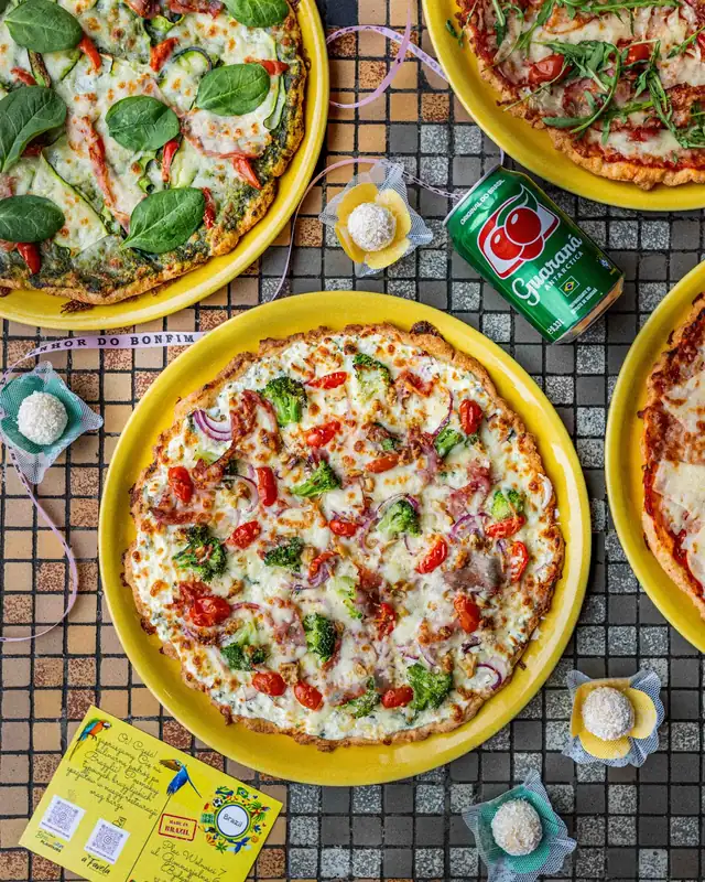 Pizze na żółtych talerzach na kolorowej mozaice, widok z góry